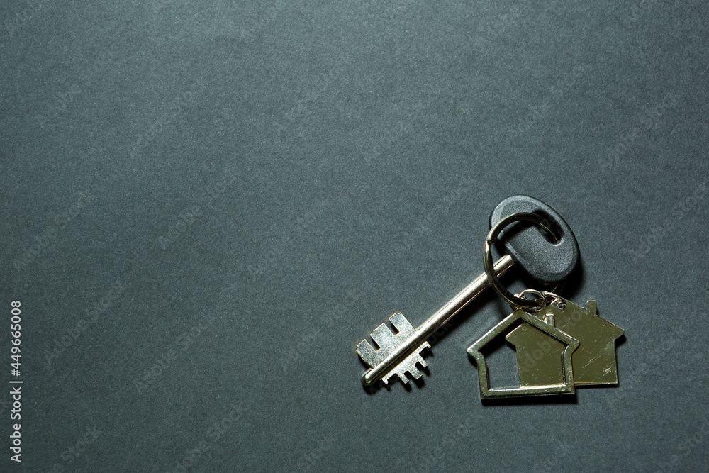 Key chain in the shape of house with key on a black background. Building, design, project, moving to new home, mortgage, deposit, rent and purchase real estate. Copy space Key chain in the shape of house with key on a black background. Building, design, project, moving to new home, mortgage, deposit, rent and purchase real estate. Copy space