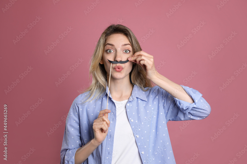 Emotional woman with fake mustache on dusty rose background