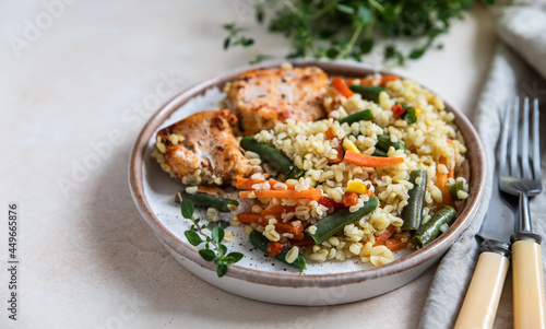 Baked chicken or turkey breast with bulgur and vegetables on a plate.