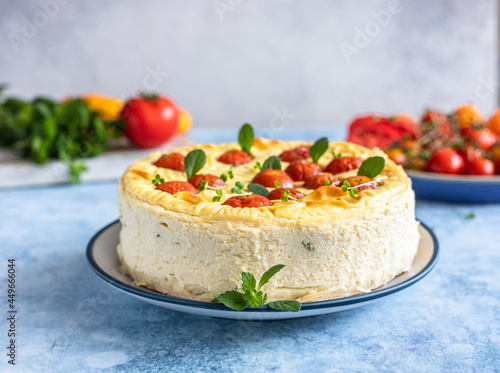 Savoury cheesecake with tomatoes decorated with mint, blue concrete background.