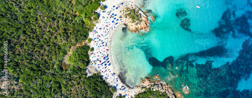 View from above, stunning panoramic view of a white sand beach full of beach umbrellas and people swimming in a turquoise water. Spiaggia del Principe, Costa Smeralda, Sardinia, Italy.