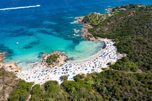 Fototapeta Naklejka Na Ścianę i Meble -  View from above, stunning aerial view of a white sand beach full of beach umbrellas and people swimming in a turquoise water. Spiaggia del Principe, Costa Smeralda, Sardinia, Italy.