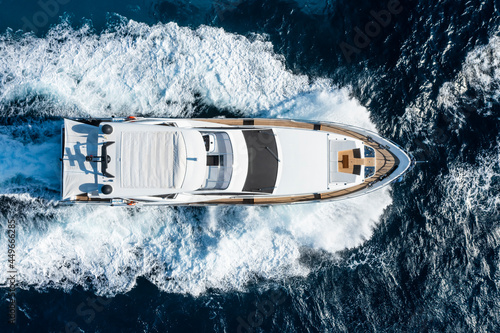 Obraz na płótnie View from above, stunning aerial view of a luxury yacht cruising on a blue water with waves crashing on the bow of the boat.Sardinia, Italy. w salonie