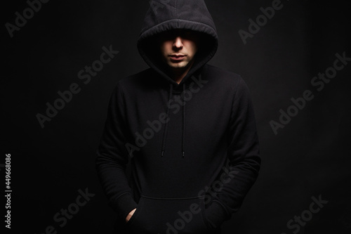Man in Black Hood in dark studio. Boy in a hooded sweatshirt