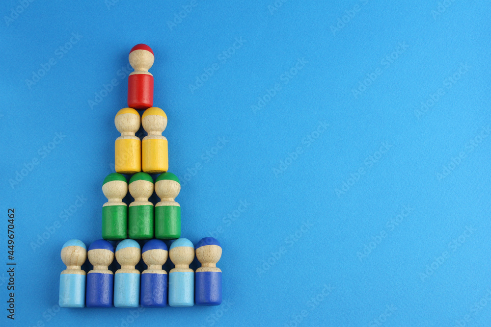 pyramid of multicolored wooden toy people on blue background with copy space, concept of social rating pyramid of multicolored wooden toy people on blue background with copy space, concept of social rating
