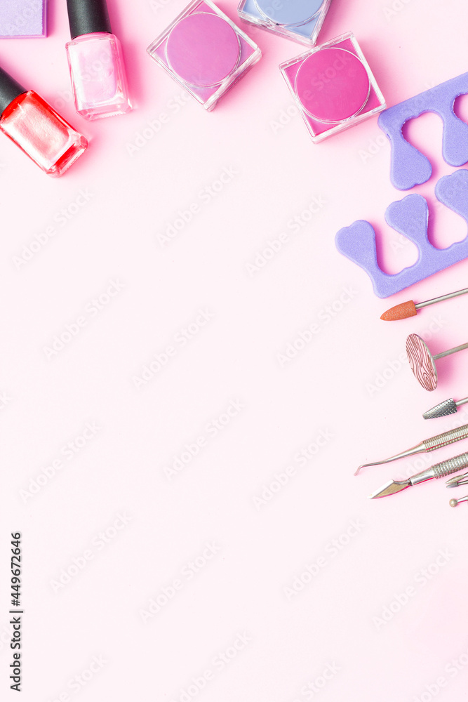 A set of cosmetics for manicure and pedicure on a pink and purple background. Gel varnishes, nail files, nail scissors, pusher, spacers and wire cutters top view. 