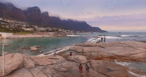 Aerial: Tourists at a tidal pool in Camps Bay coastline, Cape Town, South Africa. 20 August 2020