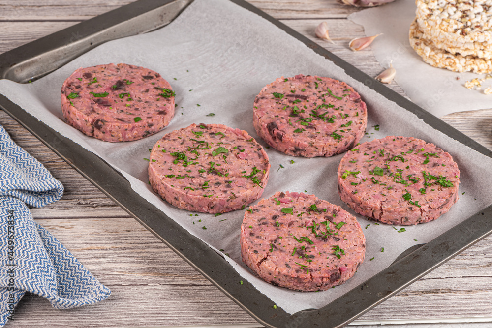 Raw veggie burger with beetroot and white beans with parsley leaves on wood cutting board. Raw veggie burger with beetroot and white beans with parsley leaves on wood cutting board.