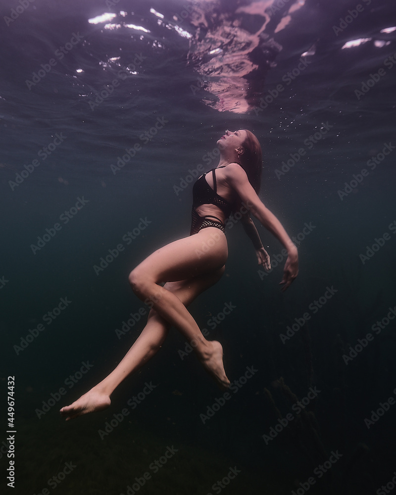 girl dives from the depths of the lake against the background of darkness