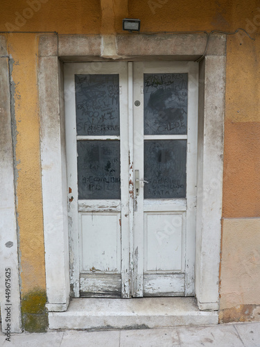 Old wooden entrance door with dusty glass. Antique door to an abandoned house in Croatia