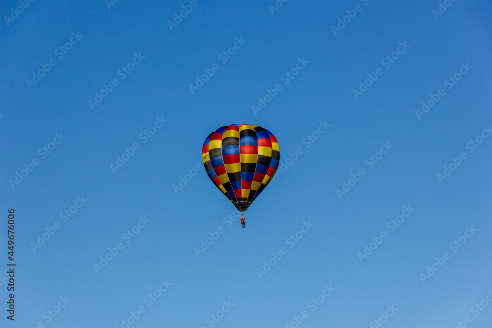 Naklejka premium Kirchberg in Tirol, Tirol/Austria - September 28 2018: A bright colorful hopper one-man hot-air balloon flying in light bright blue sky with no clouds
