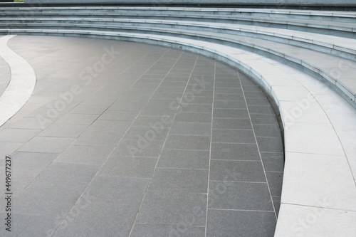 Dark gray granite tiles floor with white stairway curved shape background.