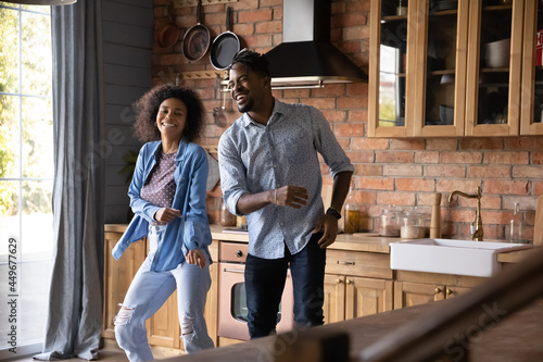Excited millennial African American man and woman have fun dance together in home kitchen. Smiling young ethnic couple renters enjoy relocation moving to new house. Rental, real estate concept.