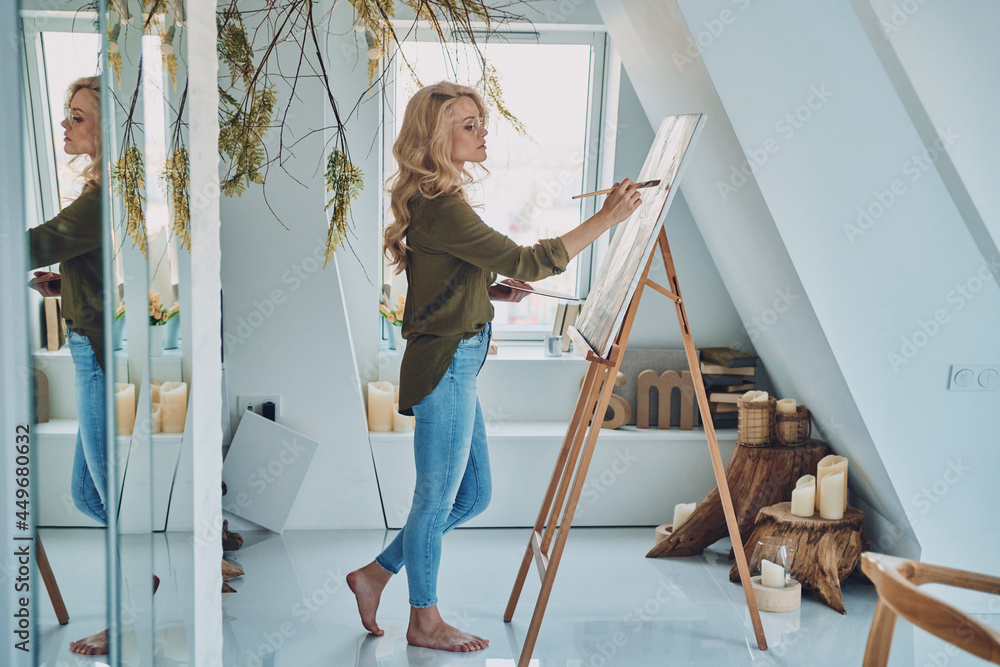 Full length of attractive young woman painting in art studio Full length of attractive young woman painting in art studio