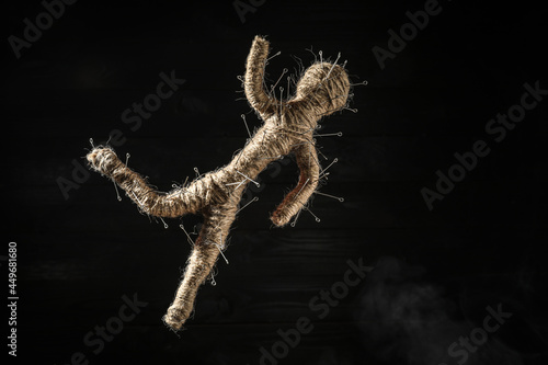 Foto Voodoo doll with pins on black wooden background