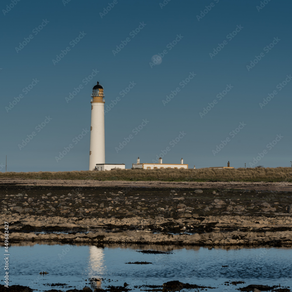 lighthouse on the coast with the full moon rising behind