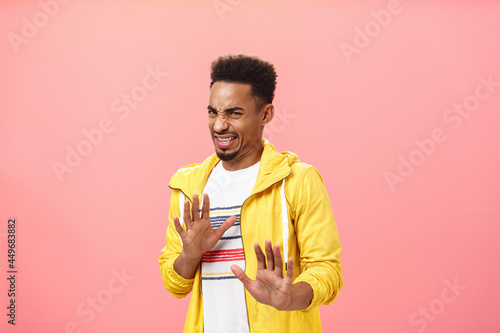 Guy prefers staying out of troubles. Disgusted displeased handsome dark-skinned man with afro hairstyle wrinkling nose and clenching teeth in disgust raising hands in rejection or refusal from dislike