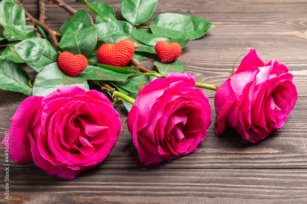 Fototapeta premium beautiful roses and knitted hearts on a wooden background