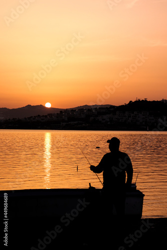 silhouette of a person sitting on a pier