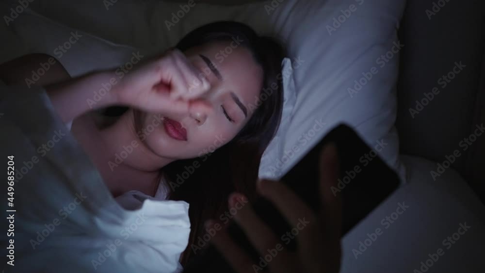 Closeup Asian woman got eye pain using smartphone on a bed at night Closeup Asian woman got eye pain using smartphone on a bed at night