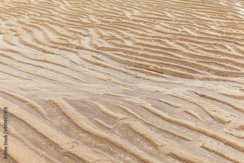 Light brown sand curls after the sea water recedes pattern and background texture photo