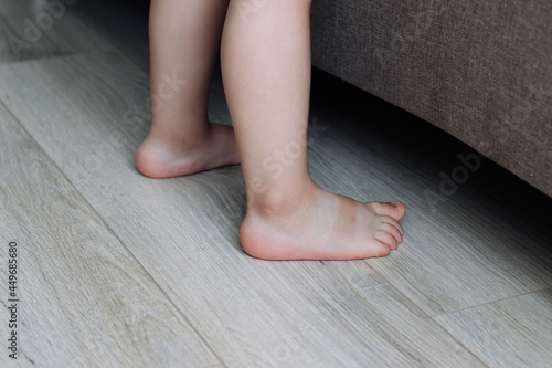 Barefoot toddler's feet on wooden floor.