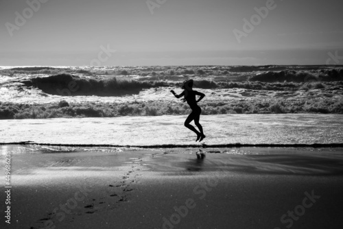 pretty young woman running barefoot on the beach