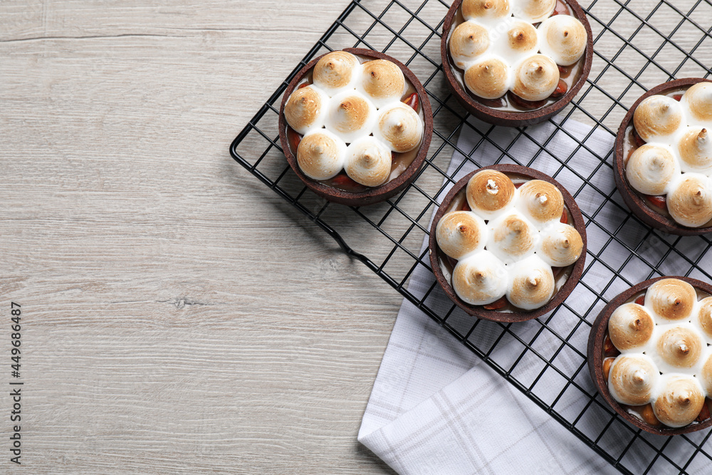 Delicious salted caramel meringue tarts on light wooden table, flat lay. Space for text Delicious salted caramel meringue tarts on light wooden table, flat lay. Space for text