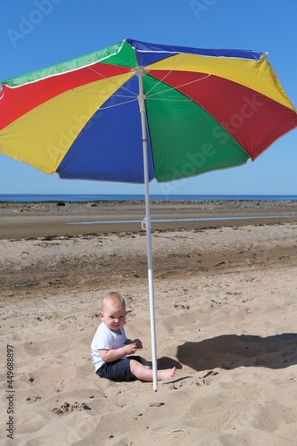 child plays on the beach of the White Sea under an umbrella.