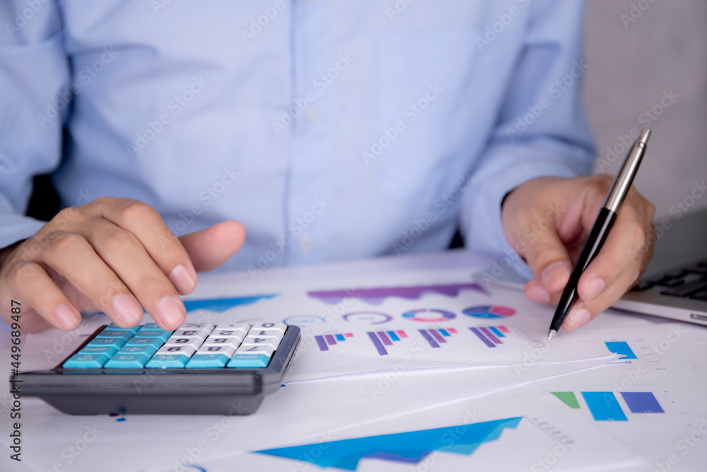 Hands of businessman calculate tax with calculator while laptop computer on desk, man planning finance and investment with graph and chart, statistic and examining account, business concept. Hands of businessman calculate tax with calculator while laptop computer on desk, man planning finance and investment with graph and chart, statistic and examining account, business concept.