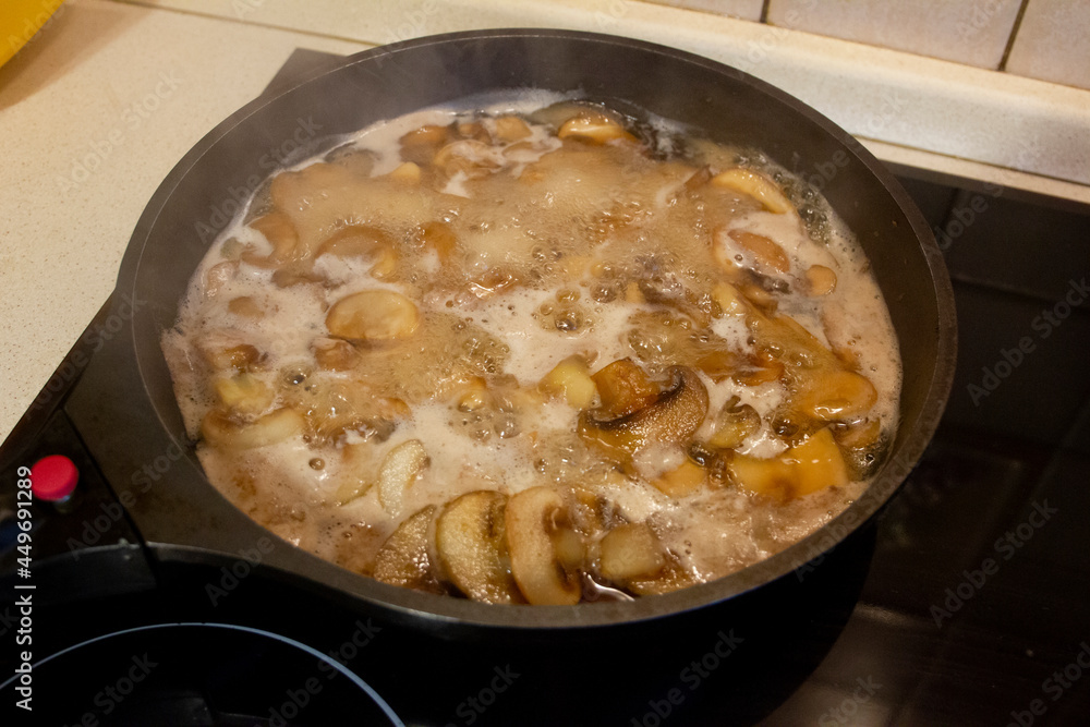 Sliced frozen mushrooms are fried in a frying pan