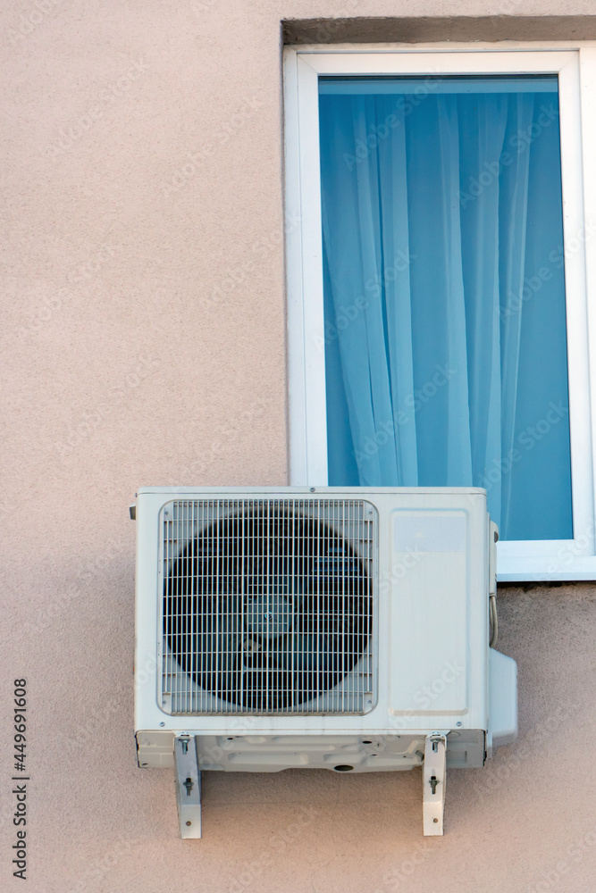 An outdoor air conditioner unit installed on the wall of a residential building next to the window. Installation, repair and maintenance of air conditioning systems in residential premises. An outdoor air conditioner unit installed on the wall of a residential building next to the window. Installation, repair and maintenance of air conditioning systems in residential premises.