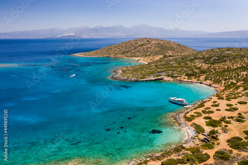 Aerial view of a crystal clear blue ocean and hot, summer landscape with tourist boats (Crete, Greece)