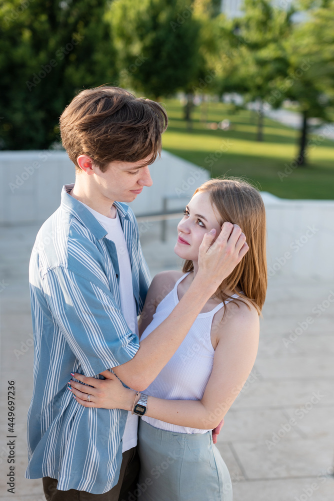 Fototapeta premium Couple of teenagers holding hands and hugging in the park. The first love