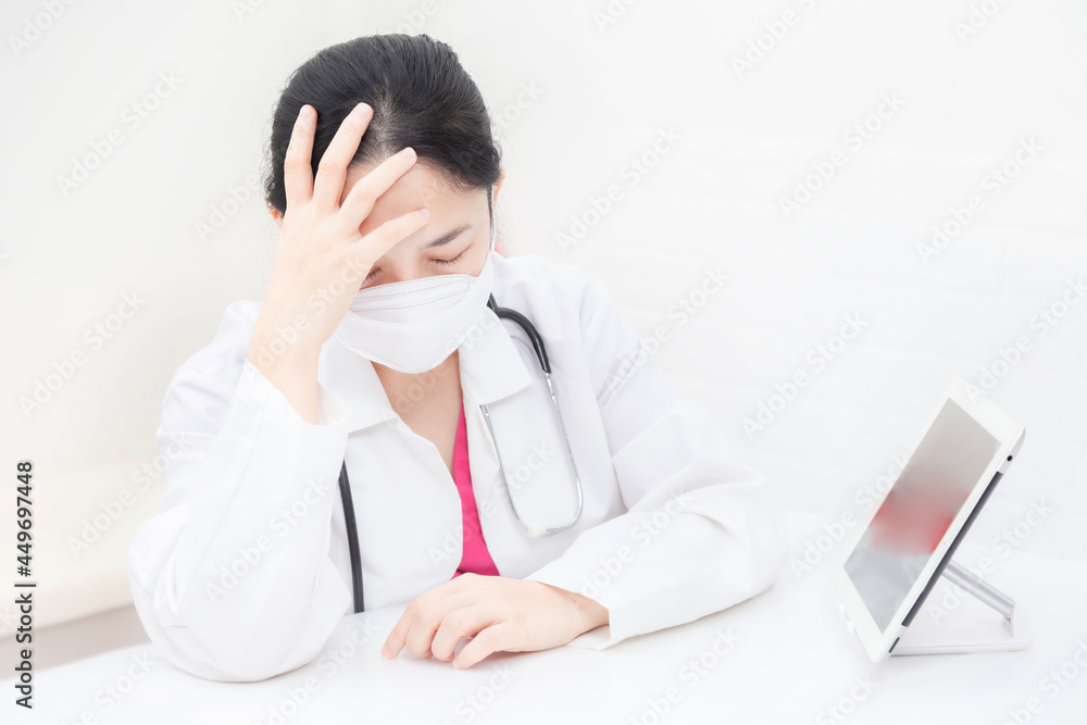 The female doctor sitting on desk is stressed and tired in the office. health care and prevention COVID-19 strategy Coronavirus concept The female doctor sitting on desk is stressed and tired in the office. health care and prevention COVID-19 strategy Coronavirus concept
