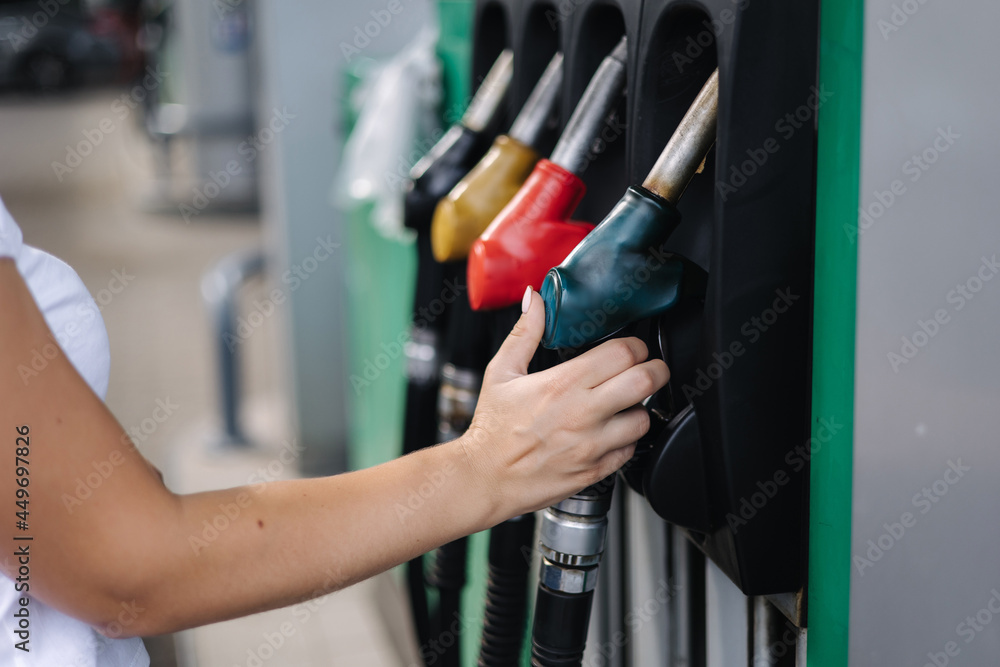 Close-up of a women's hand using a fuel nozzle at a gas station. Petrol station concept. Filling station at petrol gasoline