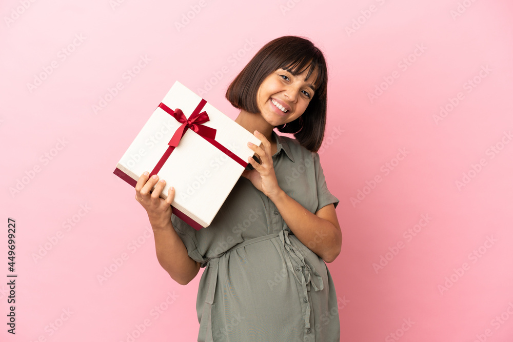 Woman over isolated background pregnant and holding a gift Woman over isolated background pregnant and holding a gift