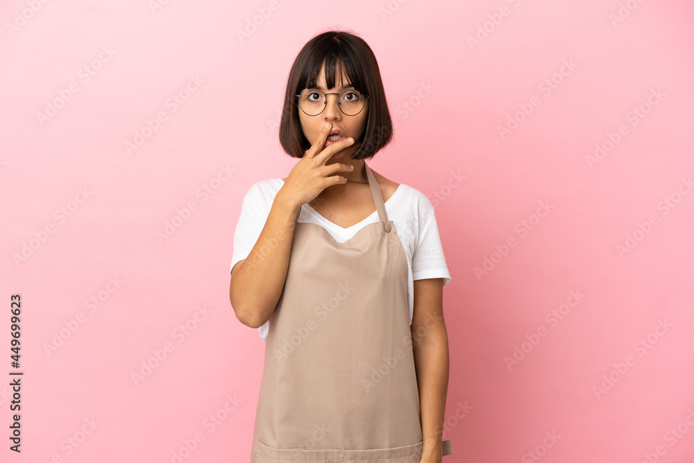Restaurant waiter over isolated pink background surprised and shocked while looking right Restaurant waiter over isolated pink background surprised and shocked while looking right