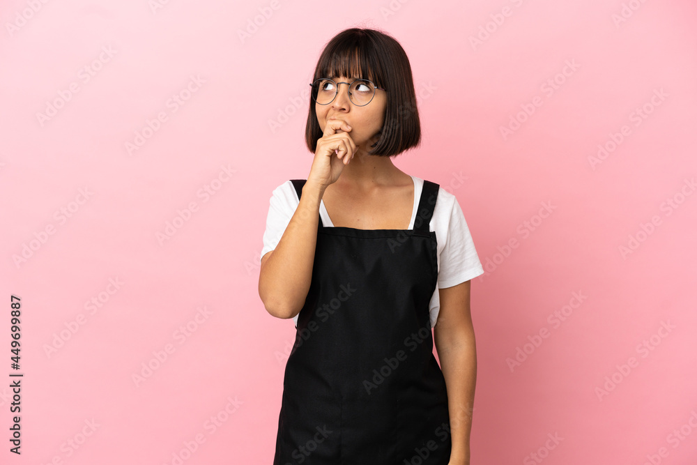 Restaurant waiter over isolated pink background having doubts and with confuse face expression Restaurant waiter over isolated pink background having doubts and with confuse face expression