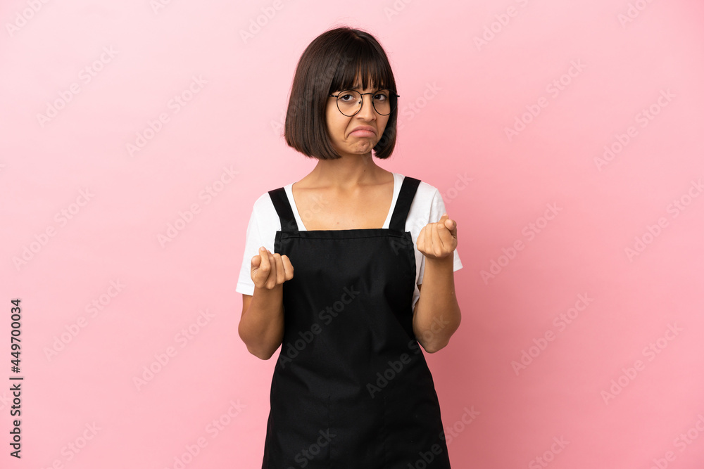 Restaurant waiter over isolated pink background making money gesture but is ruined Restaurant waiter over isolated pink background making money gesture but is ruined
