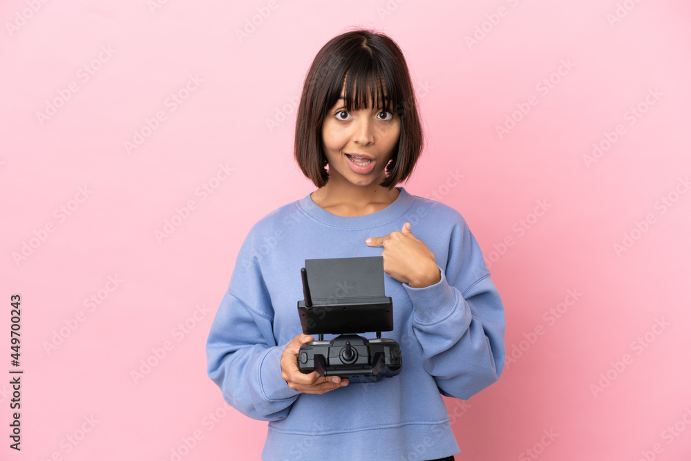 Young mixed race woman holding a drone remote control isolated on pink background with surprise facial expression Young mixed race woman holding a drone remote control isolated on pink background with surprise facial expression