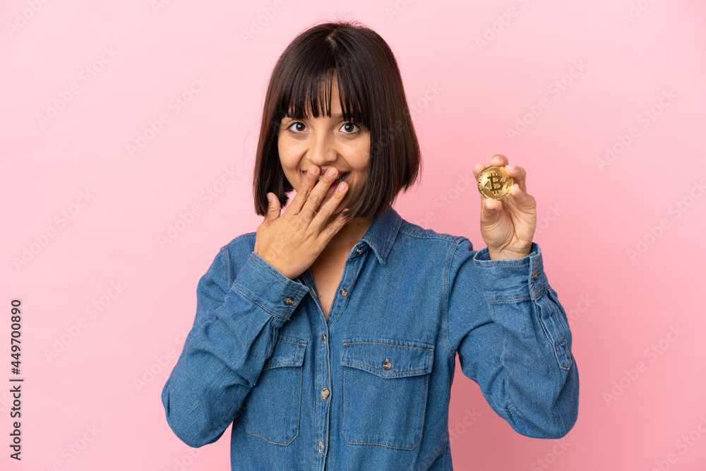 Young mixed race woman holding a Bitcoin isolated background happy and smiling covering mouth with hand Young mixed race woman holding a Bitcoin isolated background happy and smiling covering mouth with hand