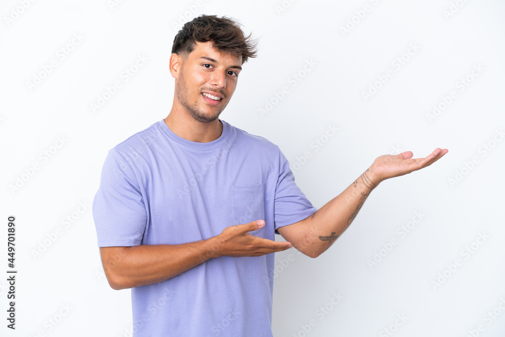 Young caucasian handsome man isolated on white background extending hands to the side for inviting to come Young caucasian handsome man isolated on white background extending hands to the side for inviting to come