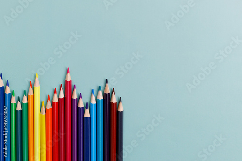 Colored sharpened pencils lie on a blue background with space for copying. School supplies or school preparation. Top view.