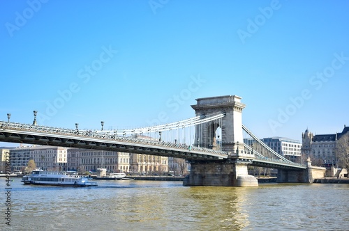 The Széchenyi Chain Bridge is a suspension bridge that spans the River Danube between Buda and Pest, the western and eastern sides of Budapest.
