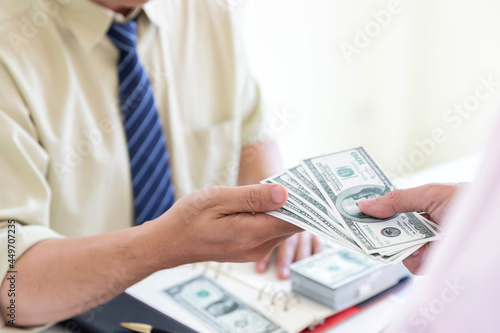 Man offering batch of hundred dollar bills. Hand of a businessman giving money to his partner. Hand receiving money from businessman. Venality, bribe, corruption concept.