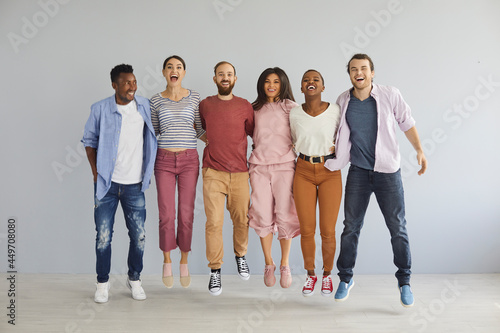 Diverse group of happy young people jumping in studio. Bunch of cheerful positive excited international multicultural mixed race college students in casual clothes jumping together and laughing