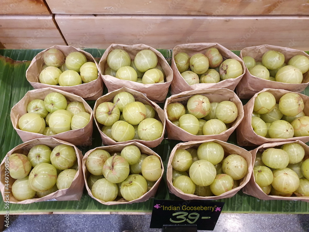 Indian Gooseberry, greenish yellow orbs packed in brown paper bags arranged on wooden trays with price tags. Scientific name Phyllanthus emblica Linn. It is a herb with high anti-oxidants and vitaminC