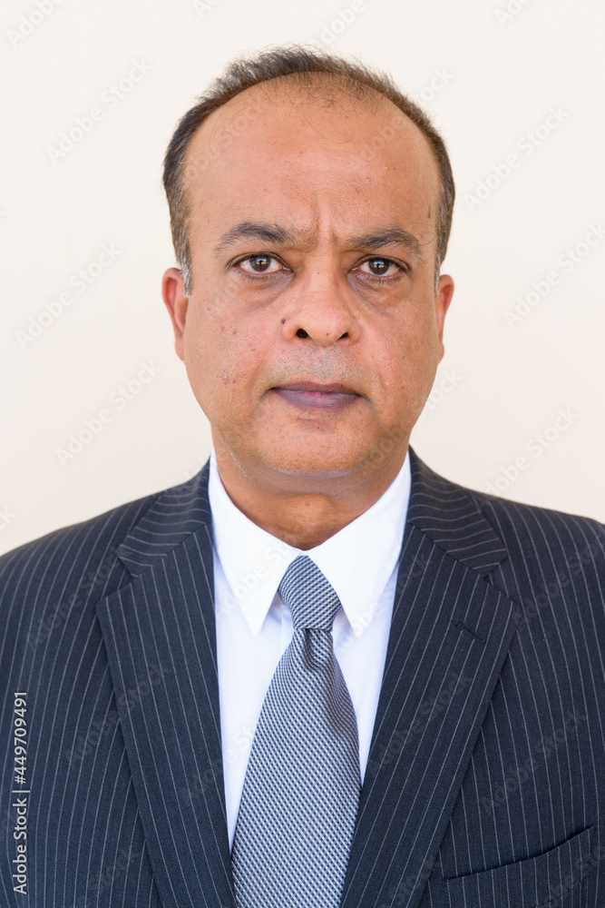 Portrait of Indian businessman against plain wall outdoors Portrait of Indian businessman against plain wall outdoors