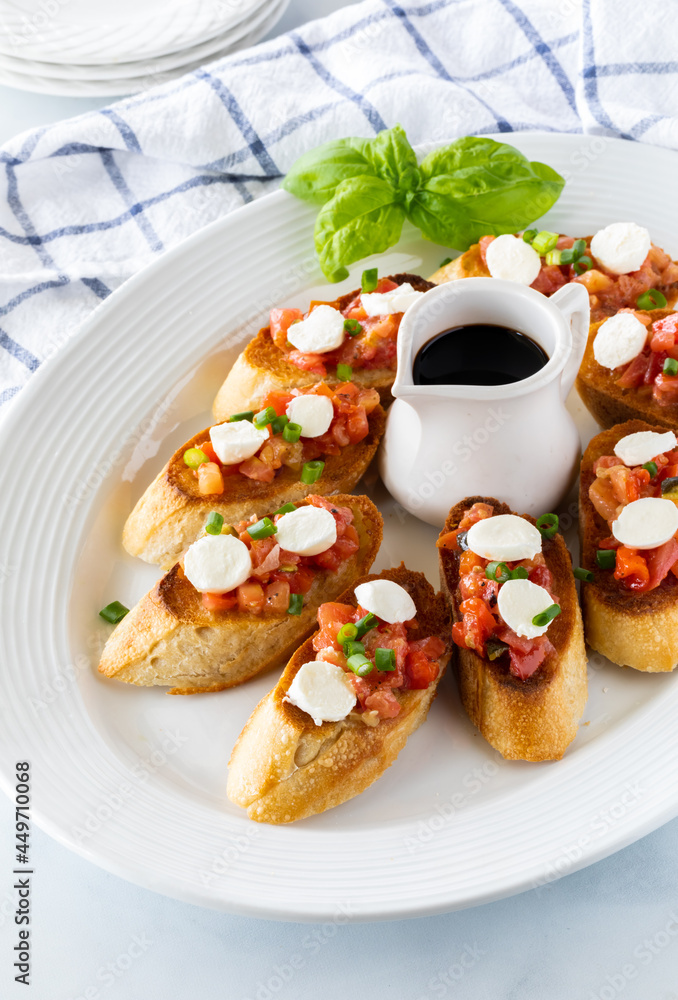 Close up of a platter filled with homemade bruschetta served with balsamic vinegar, ready for eating. Close up of a platter filled with homemade bruschetta served with balsamic vinegar, ready for eating.